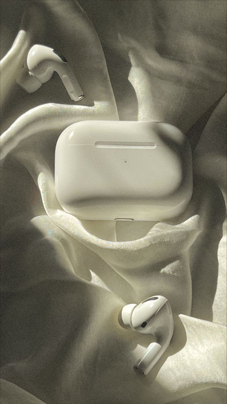 White wireless earbuds and charging case on a textured surface